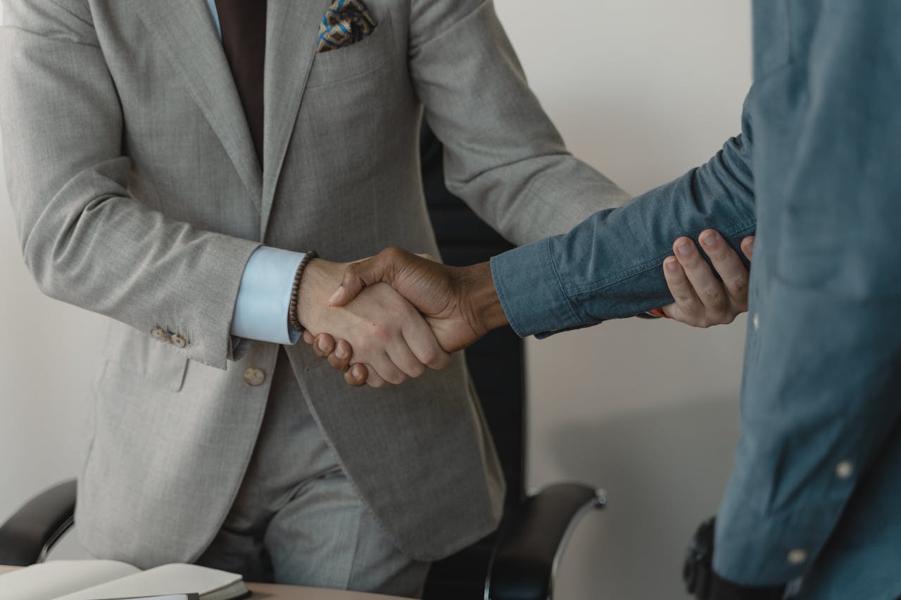 Dwóch mężczyzn podających sobie dłonie – symbol współpracy biznesowej i potencjalnych zmów cenowych kontrolowanych przez Inspekcję Handlową.